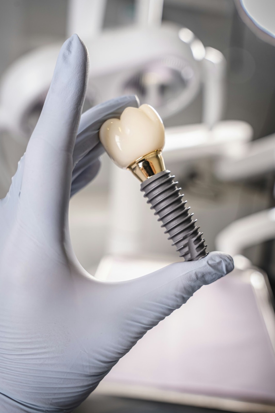 Gloved hand holding an implant with a crown