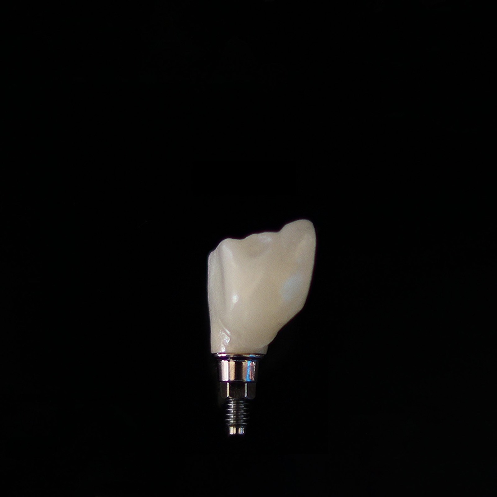 A ceramic implant crown on a black background
